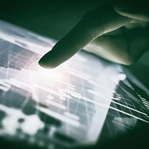 Dedo a interagir com um ecrã tátil que exibe gráficos financeiros e dados digitais, representando tecnologia e negociação online.