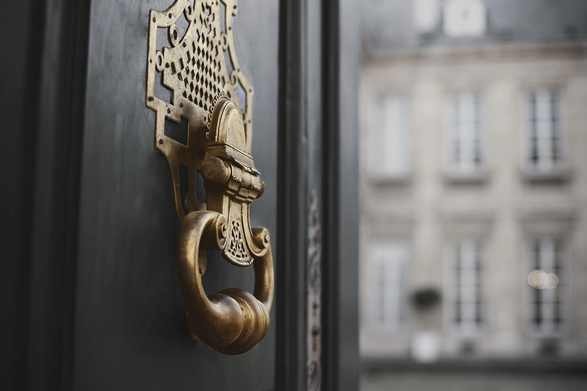 Detalhe de um puxador clássico exterior de uma porta ornamentado, simbolizando a representação física de um legado imaterial com um serviço de assessoria desenhado à medida