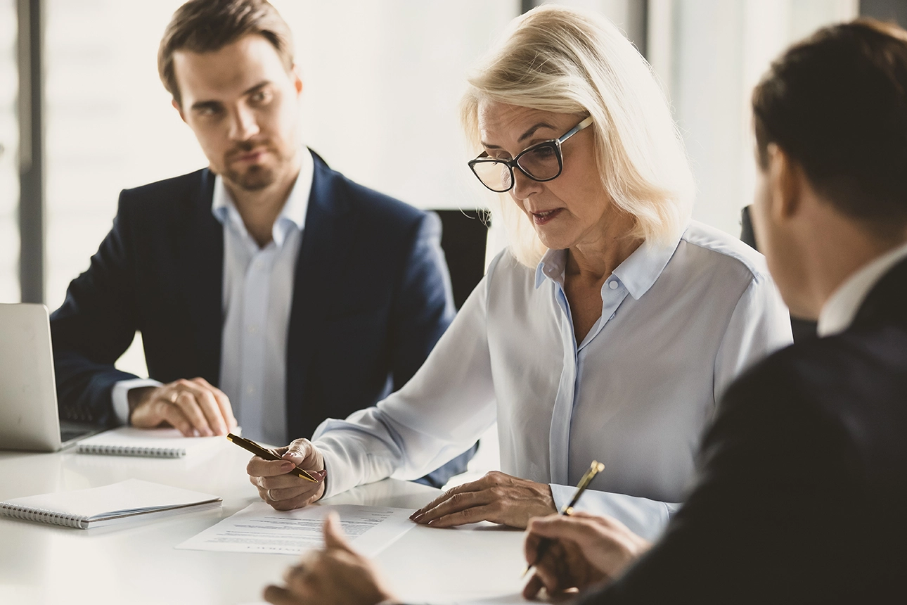 Reunião formal de três pessoas, simbolizando o acompanhamento dos clientes do Banco Carregosa