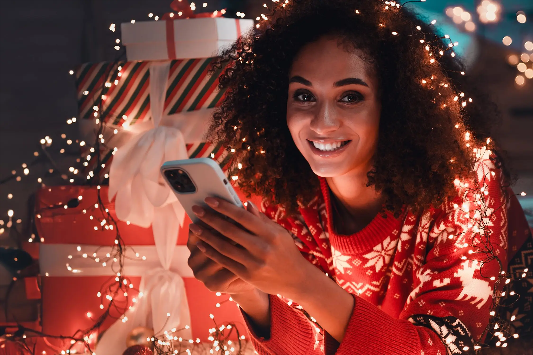 A girl with a cup and a cell phone in a room with a Christmas atmosphere