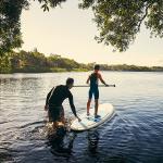 Pai e filho em paddle no rio. Simboliza novo cliente Banco Carregosa e relação duradoura.