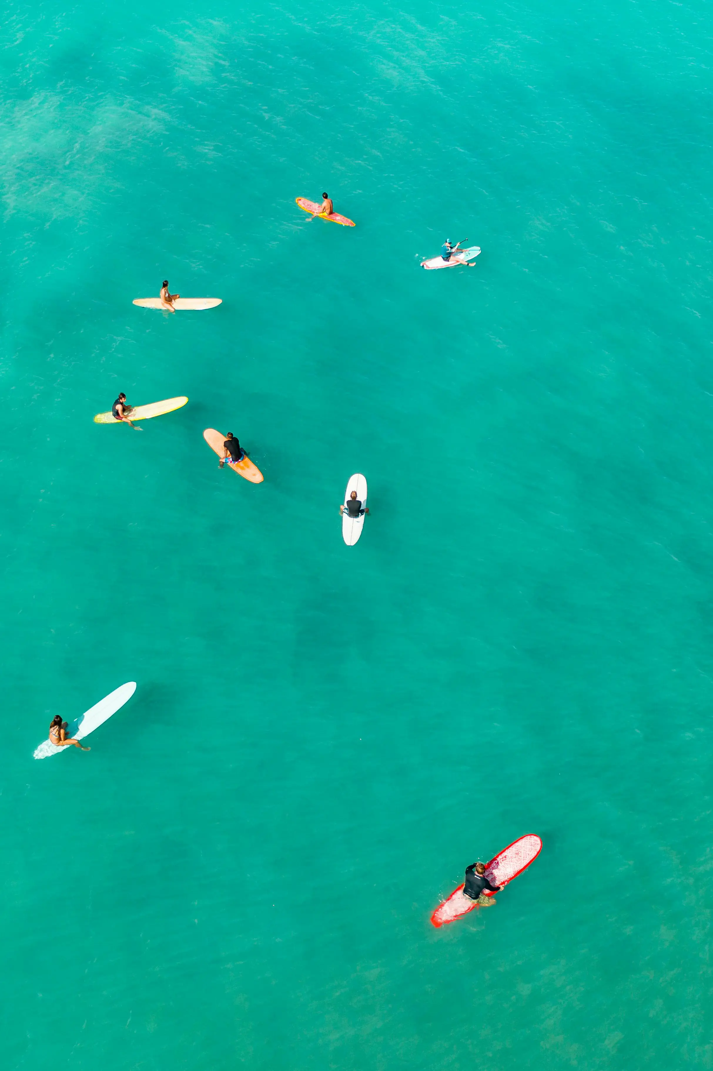 Vários surfistas vistos de cima em águas claras, ilustrando a transparência dos ETFs.