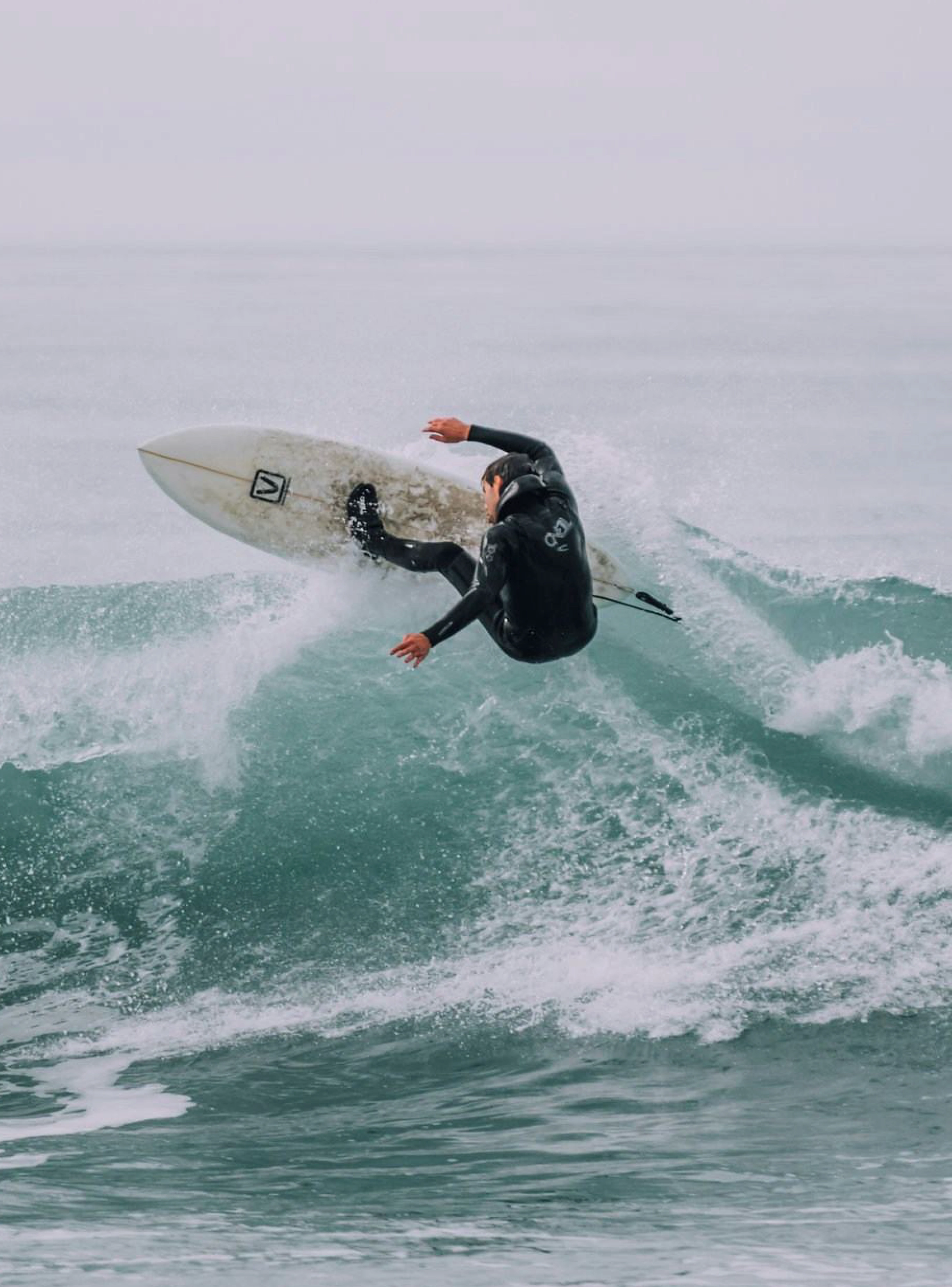 Surfista a realizar uma manobra numa onda, transmitindo energia, aventura e dinamismo.