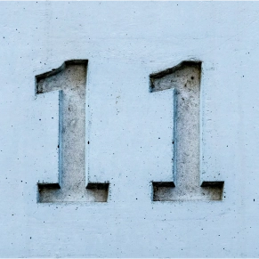 Número 11 gravado em relevo numa superfície de cimento cinzento.