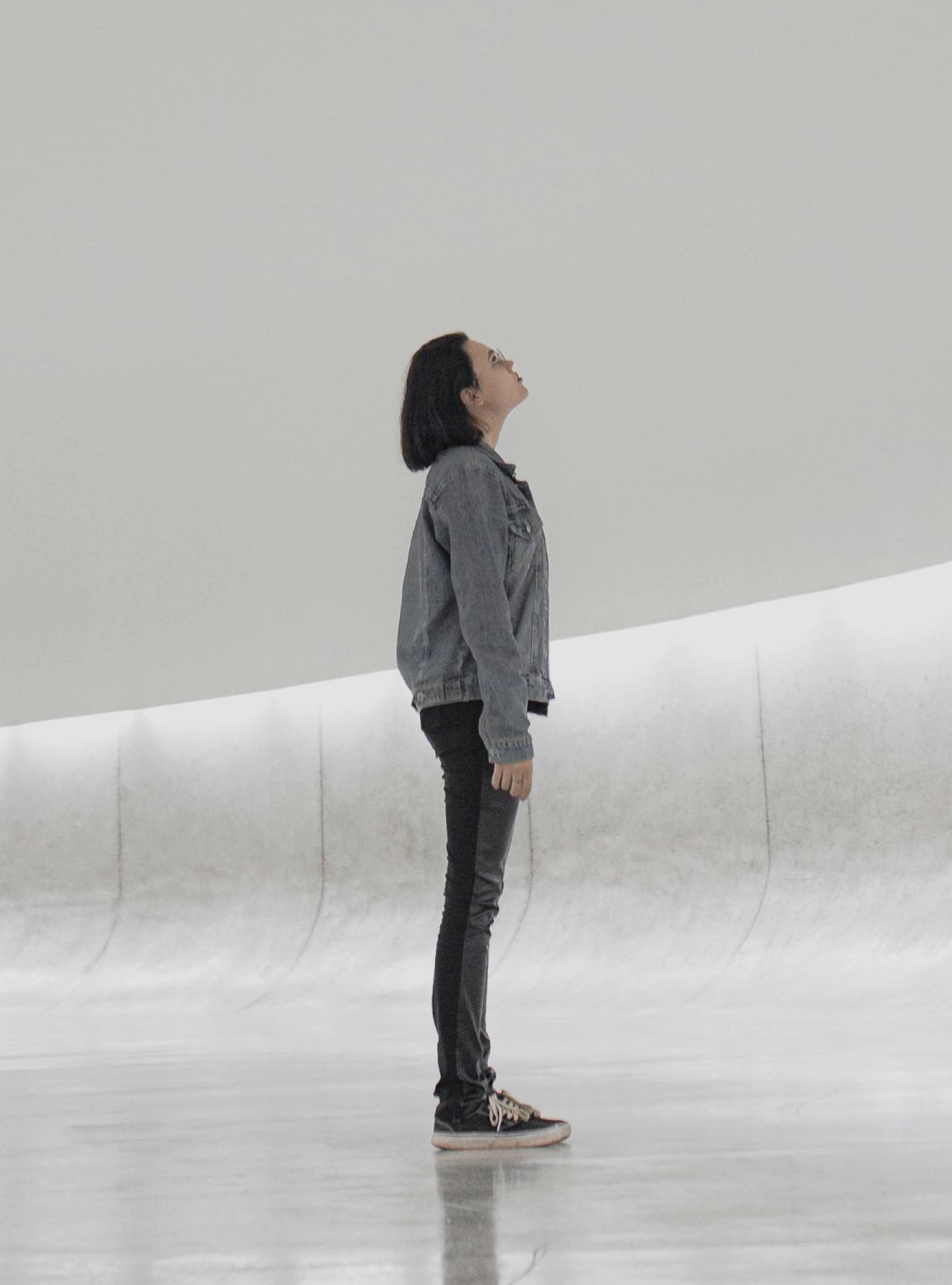 Mulher de pé de perfil a olhar para cima, numa atmosfera luminosa.