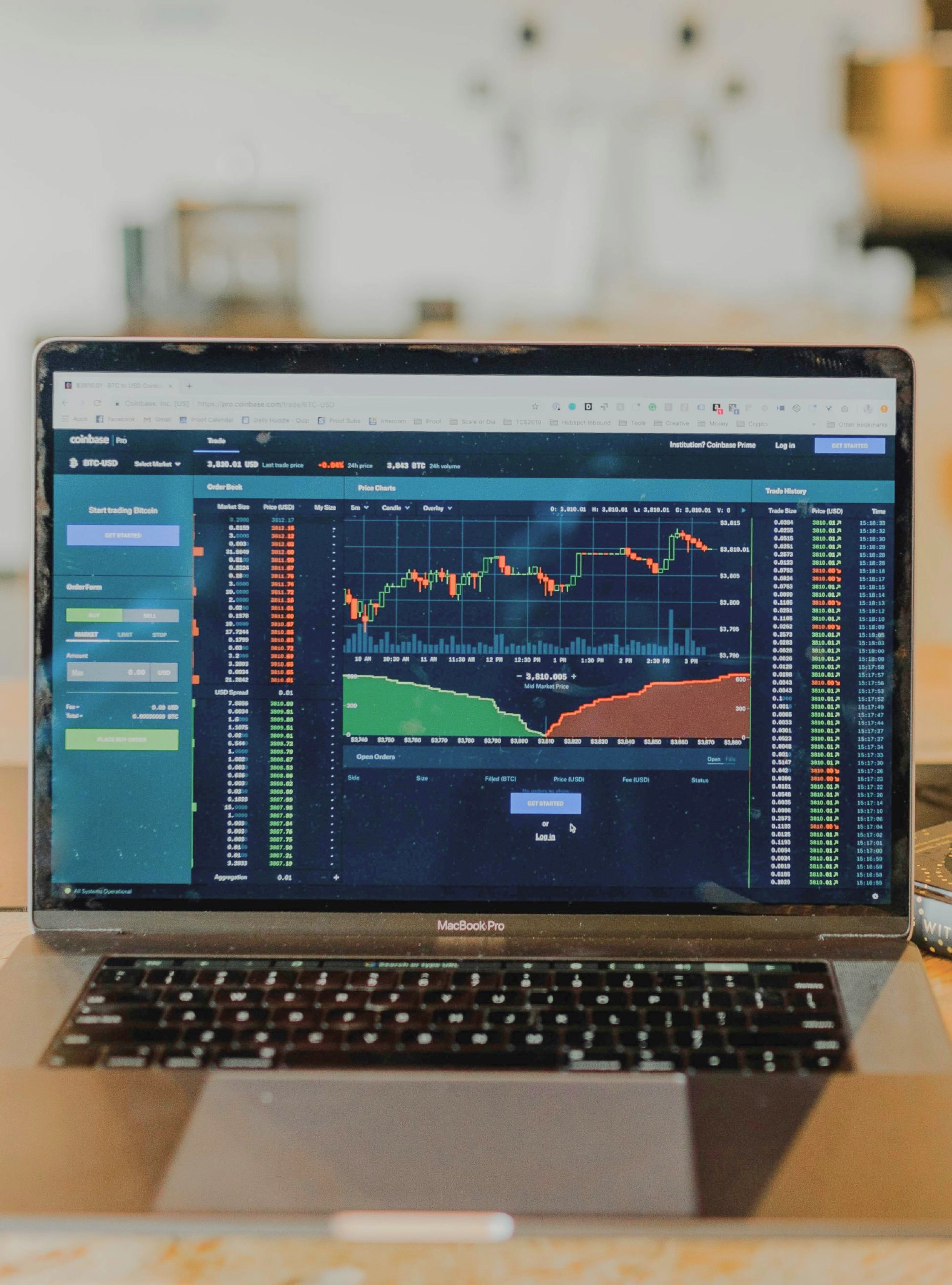 Um computador portátil numa mesa de madeira, com um ecrã onde se consegue ver gráficos de barras e linhas referentes a investimentos.