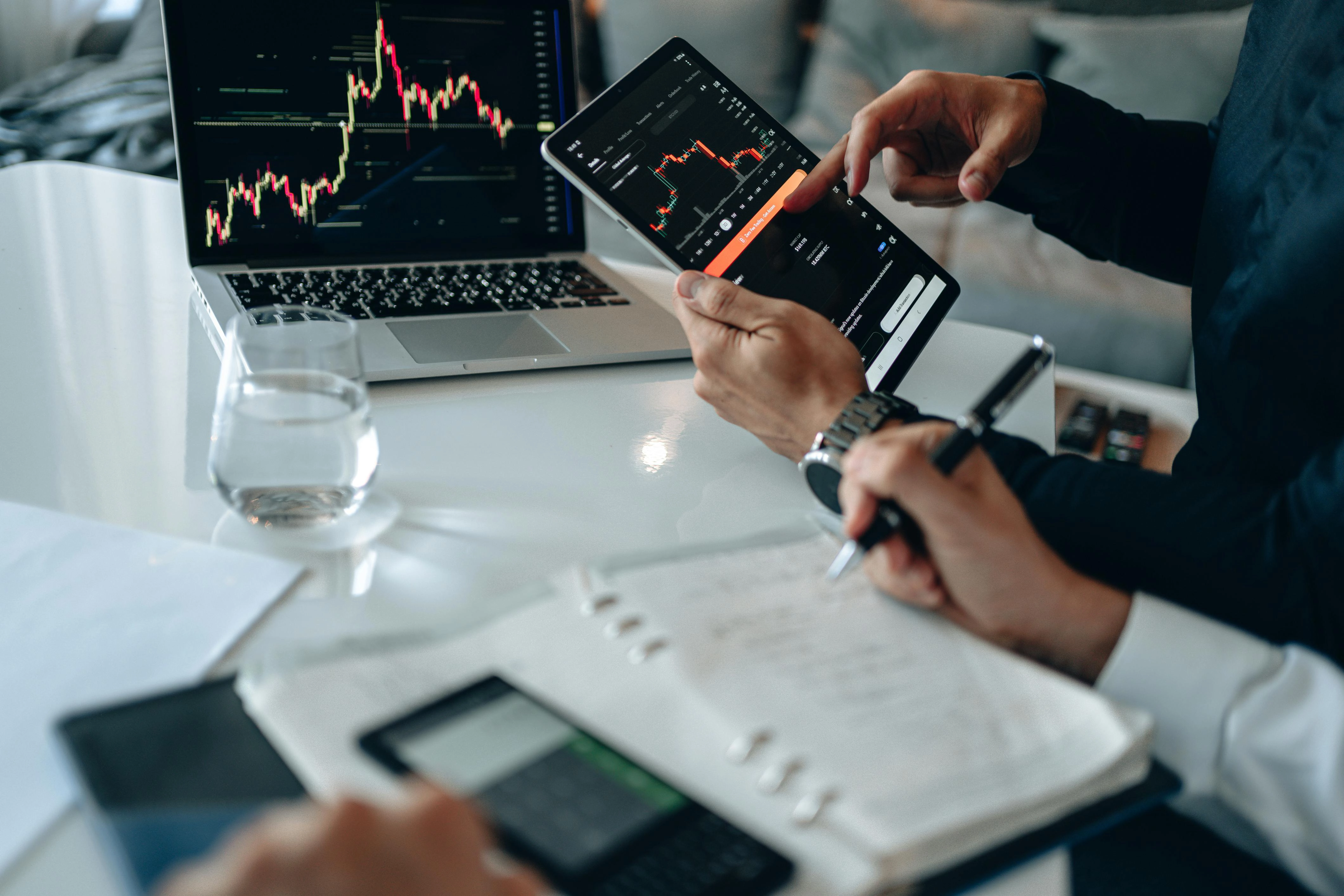 Reunião com visualização de gráficos no tablet e no computador, simbolizando os serviços desempenhados pela Intermediação Financeira