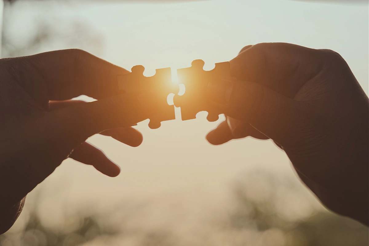 Plano aproximado de uma pessoa a juntar duas peças de um puzzle, simbolizando o investimento através de várias estratégias