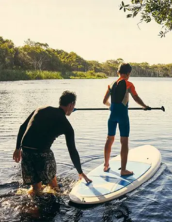 Father and son on river paddleboard. Symbolises new Banco Carregosa client and lasting bond.